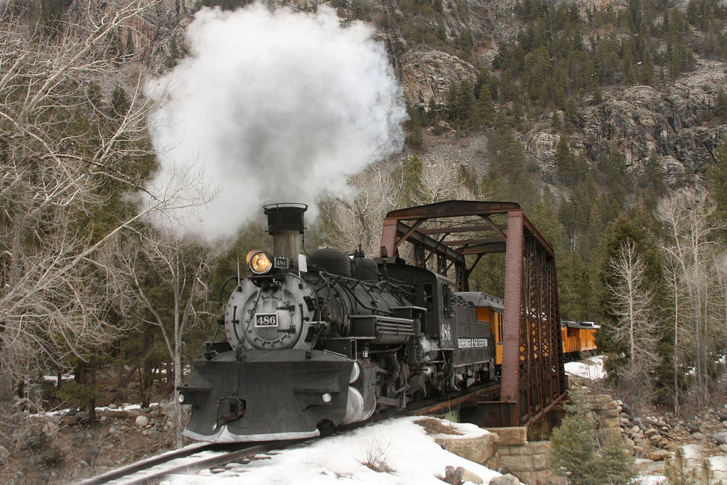 a steam engine is on a train track with smoke coming out of it