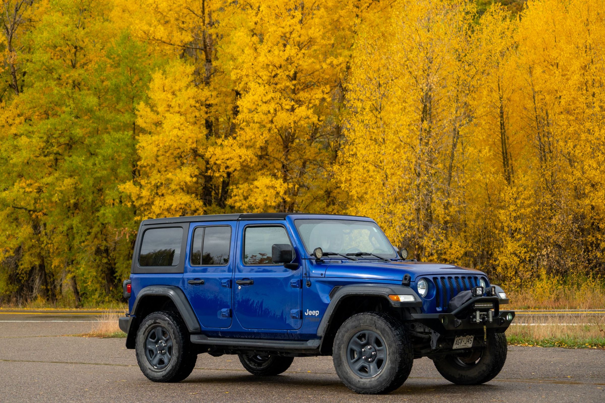 Blue Jeep fall colors1 a blue truck parked in front of a forest