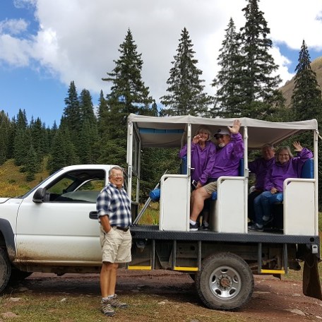 man standing beside tour jeep full of people